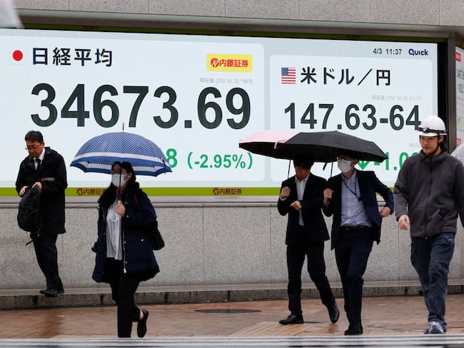 FOTODELDÍA TOKIO (Japón), 03/04/2025.- Peatones pasan junto a un panel electrónico de la bolsa que muestra el índice Nikkei de Japón, que bajó 1.052,18 puntos hasta los 34.673,69 en Tokio, Japón, este jueves. El Nikkei de Japón reacciona mientras los mercados globales se tambalean por el impacto de los nuevos aranceles radicales impuestos por el presidente estadounidense Donald Trump.- EFE/ Rodrigo Reyes Marin