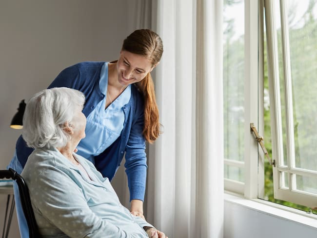 Mujer cuidando a una adulta mayor (Foto vía Getty Images)