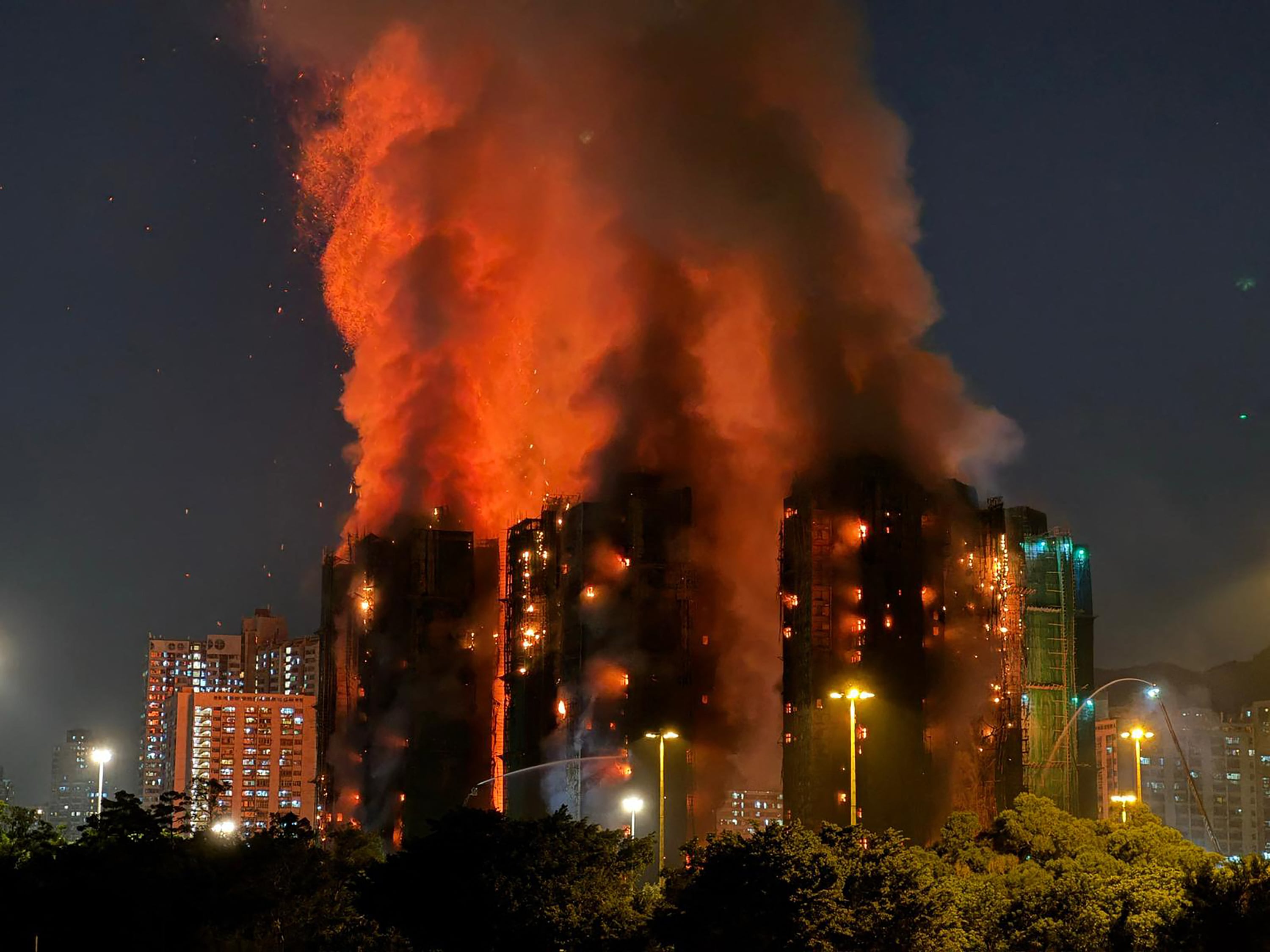 Thick smoke and flames rise as a major fire engulfs several apartment blocks at the Wang Fuk Court residential estate in Hong Kong's Tai Po district on November 26, 2025. At least four people were killed when a fire engulfed several high-rise blocks in a Hong Kong residential estate on November 26, the government said, with media reporting that some residents were trapped inside. (Photo by Yan ZHAO / AFP)