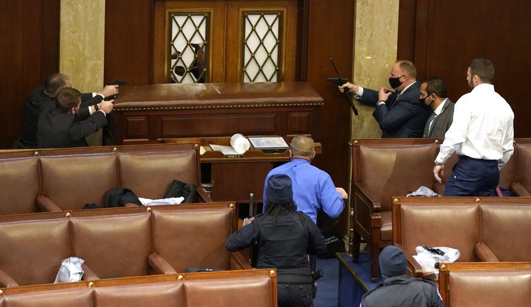 Uniformados desenfundan sus armas ante intentos de manifestantes pro Trump de entrar a la oficina central del Congreso.