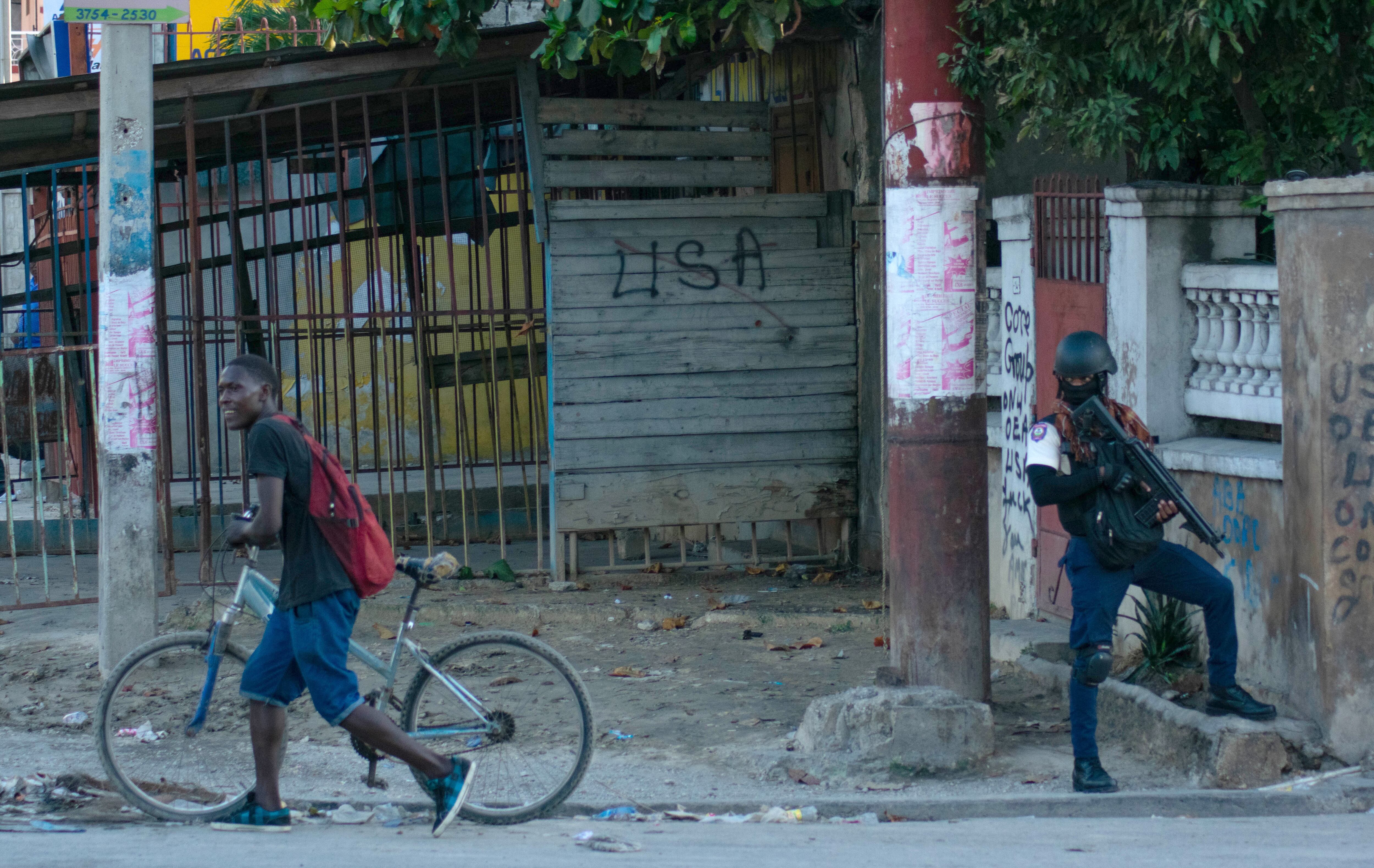 AME4788. PUERTO PRÍNCIPE (HAITÍ), 02/03/2024.- Un policía vigila durante los actos de saqueo en el centro de la ciudad, este sábado en Puerto Príncipe (Haití). Continúan los tiroteos esporádicos y los actos de saqueo este sábado en varios barrios el área metropolitana de Puerto Príncipe, creando una situación de miedo, incertidumbre y alerta constantes en la población. EFE/ Siffroy Clarens