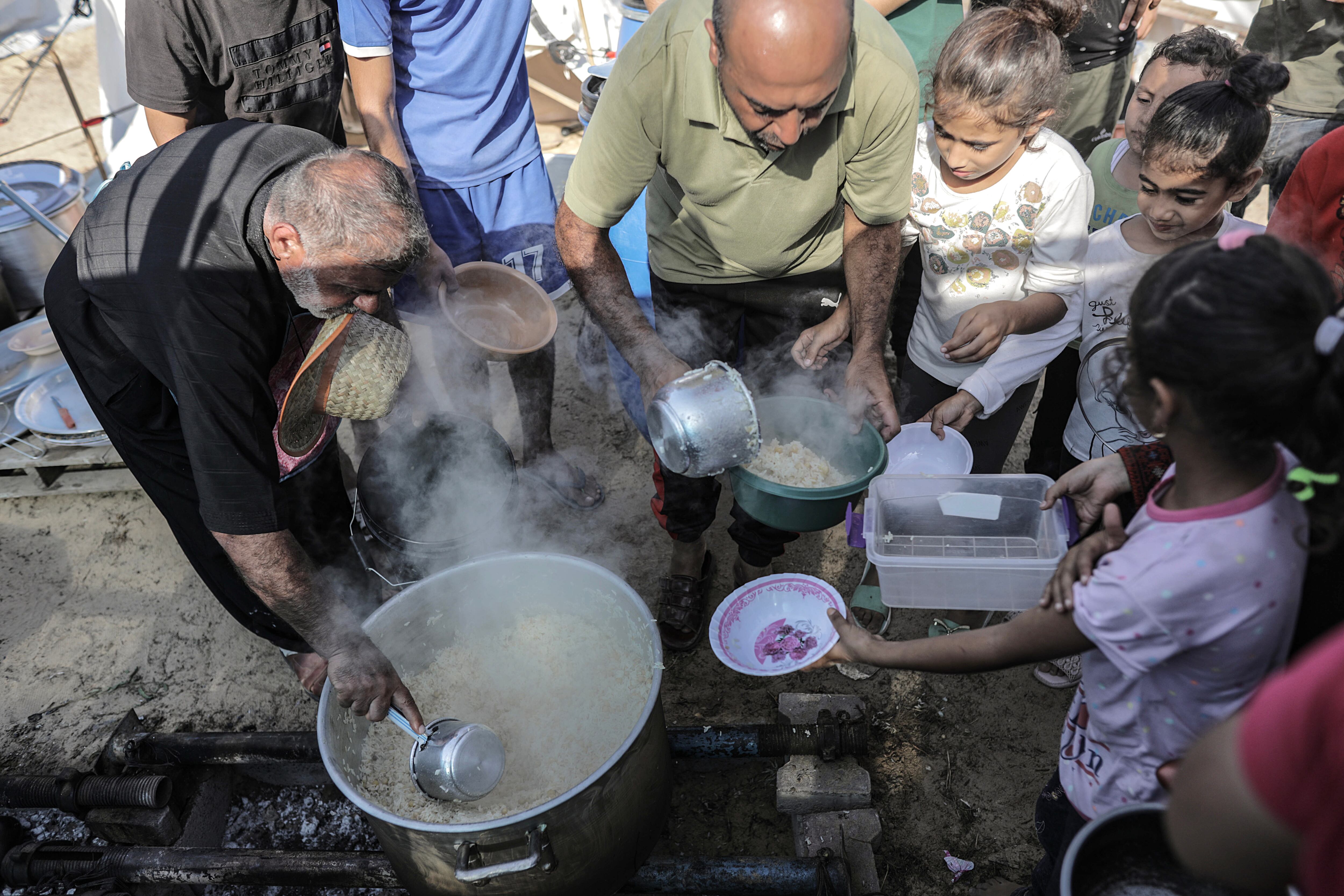 Khan Yunis (-), 25/10/2023.- Palestinian volunteers hand food to children between tents set up for Palestinians seeking refuge on the grounds of a United Nations Relief and Works Agency for Palestine Refugees (UNRWA) center at the Khan Yunis refugee camp, west of the town of Khan Yunis, southern Gaza Strip, 25 October 2023. More than 5,500 Palestinians and over 1,400 Israelis have been killed, according to the Israel Defense Forces (IDF) and the Palestinian health authority, since Hamas militants launched an attack against Israel from the Gaza Strip on 07 October, and the Israeli operations in Gaza and the West Bank which followed it. EFE/EPA/HAITHAM IMAD