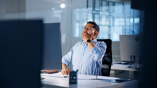 Computer, deadline and yawning with business man in office at night for overtime administration. Burnout, exhausted and fatigue with tired employee at desk in workplace for late evening report