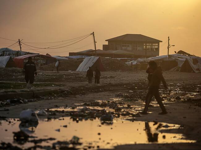 Deir Al Balah (---), 30/01/2024.- Displaced Palestinians who fled their houses from the northern Gaza Strip walk past a rain water puddle next to their shelters during a cold evening in Deir Al Balah town, southern Gaza Strip, 30 January 2024. More than 26,700 Palestinians and at least 1,330 Israelis have been killed, according to the Palestinian Health Ministry and the Israel Defense Forces (IDF), since Hamas militants launched an attack against Israel from the Gaza Strip on 07 October 2023, and the Israeli operations in Gaza and the West Bank which followed it. EFE/EPA/MOHAMMED SABER