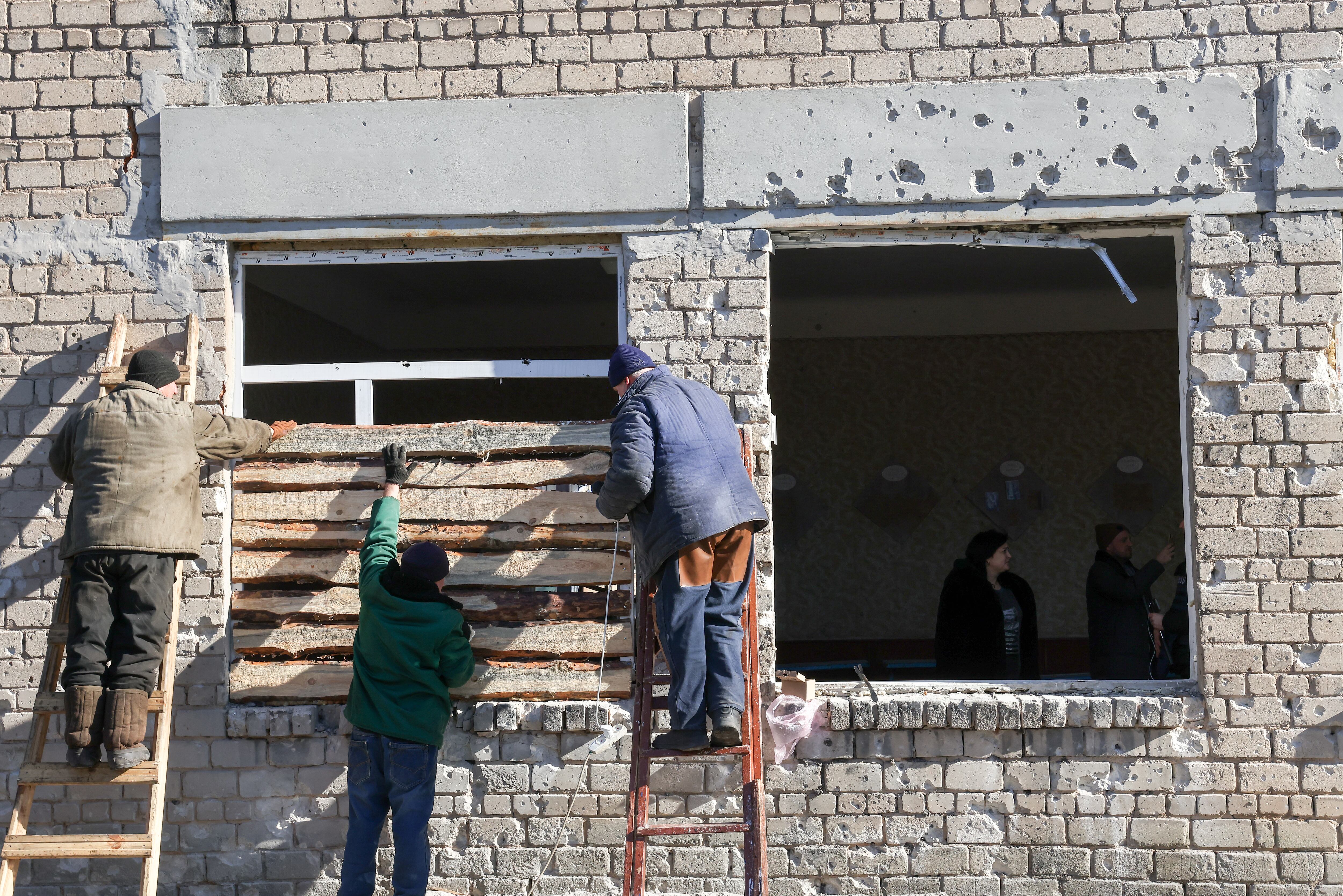 DONETSK, UKRAINE - FEBRUARY 21, 2022: People board up a window at School No 105 damaged in a shelling attack. As tension escalated in east Ukraine on 18 February, 2022, the leaders of the Donetsk and Lugansk People's Republics announced a mass evacuation of civilians to Russia. On 19 February 2022, the two republics announced general mobilisation. Alexander Ryumin/TASS (Photo by Alexander Ryumin\TASS via Getty Images)