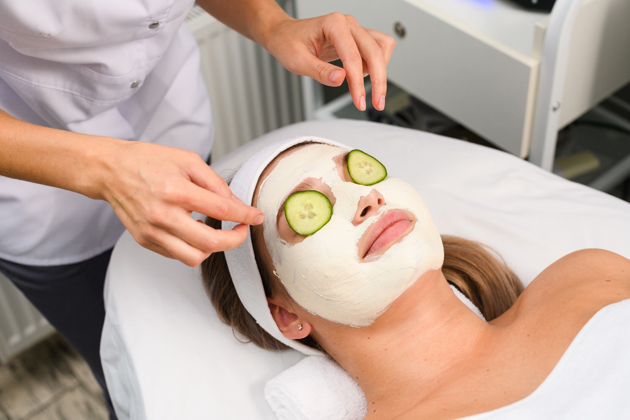 Mujer aplicando una mascarilla y colocando pepinos en los ojos de otra persona (Getty Images)