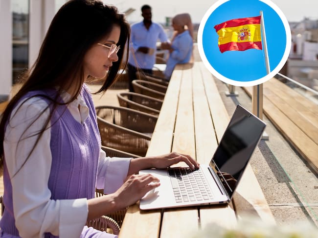Mujer trabajando desde su computadora desde un espacio abierto y de fondo la bandera de España (Foto vía Getty Images)
