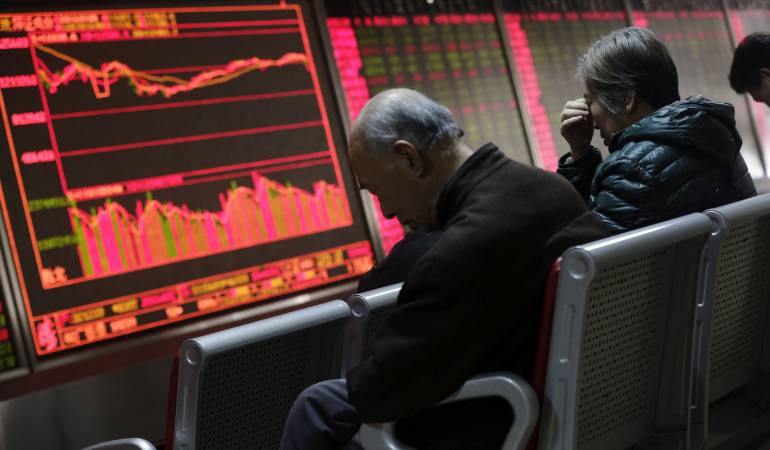 Inversores observan la información bursátil en una oficina.