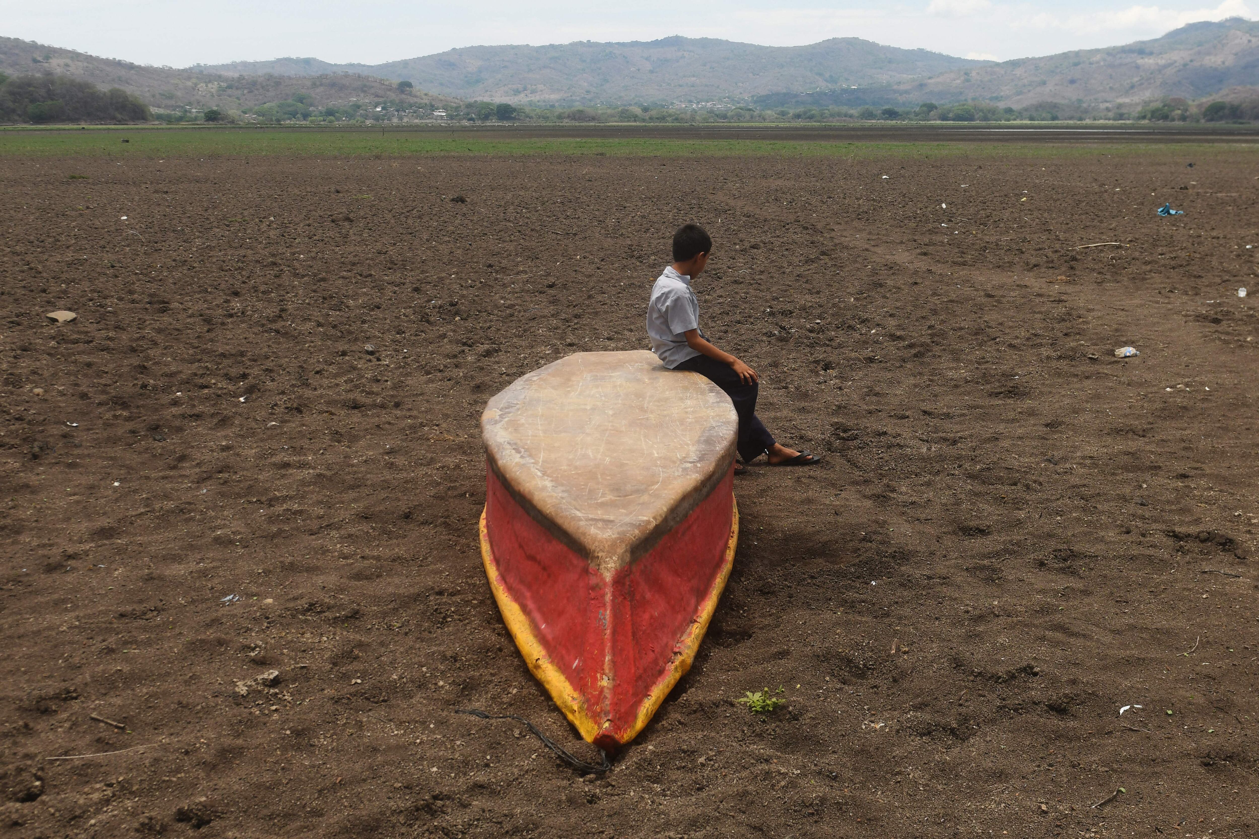 Niño sentado en una canoa en medio de lo que solía ser el lago Atescatempa, que se ha secado del todo por falta de lluvias y aumento de temperaturas en Guatemala.
(FOTO: MARVIN RECINOS/AFP via Getty Images)