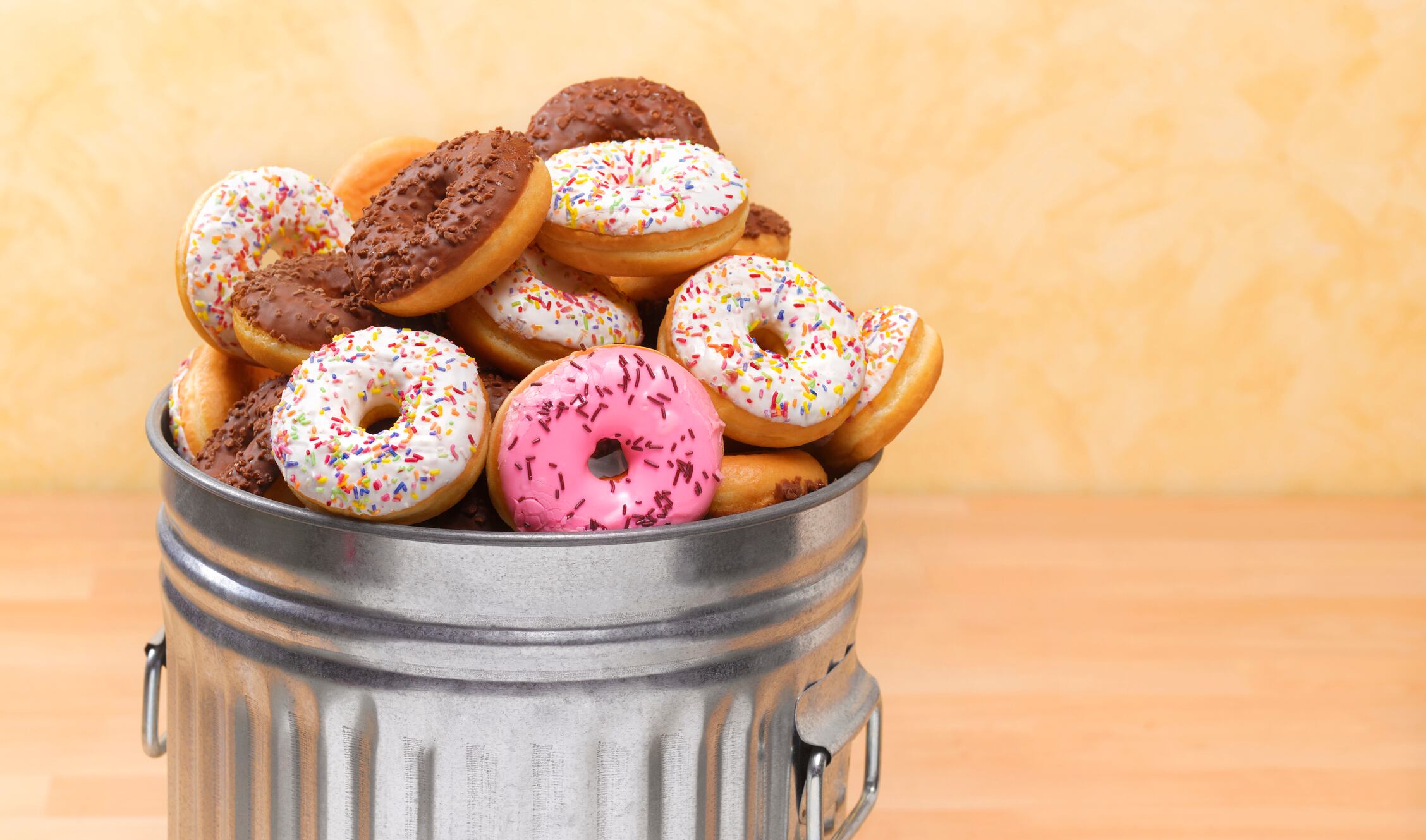 Donas de diferentes colores entre un cesto de basura (Foto vía Getty Images)