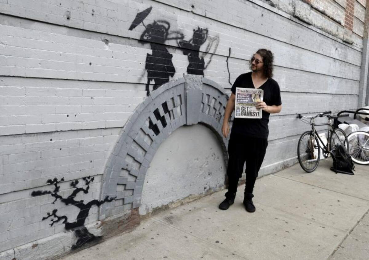 Un hombre observa el último grafiti del artista callejero Banksy en Broklyn, Nueva York.