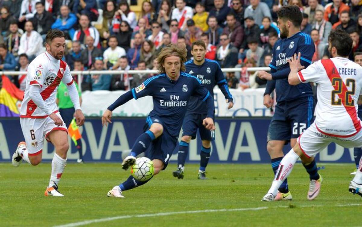 El centrocampista del Real Madrid Luka Modric (c) perseguido por Rat Razvan,iz., del Rayo Vallecano, durante el partido correspondiente a la trigésimo quinta jornada de la Liga.