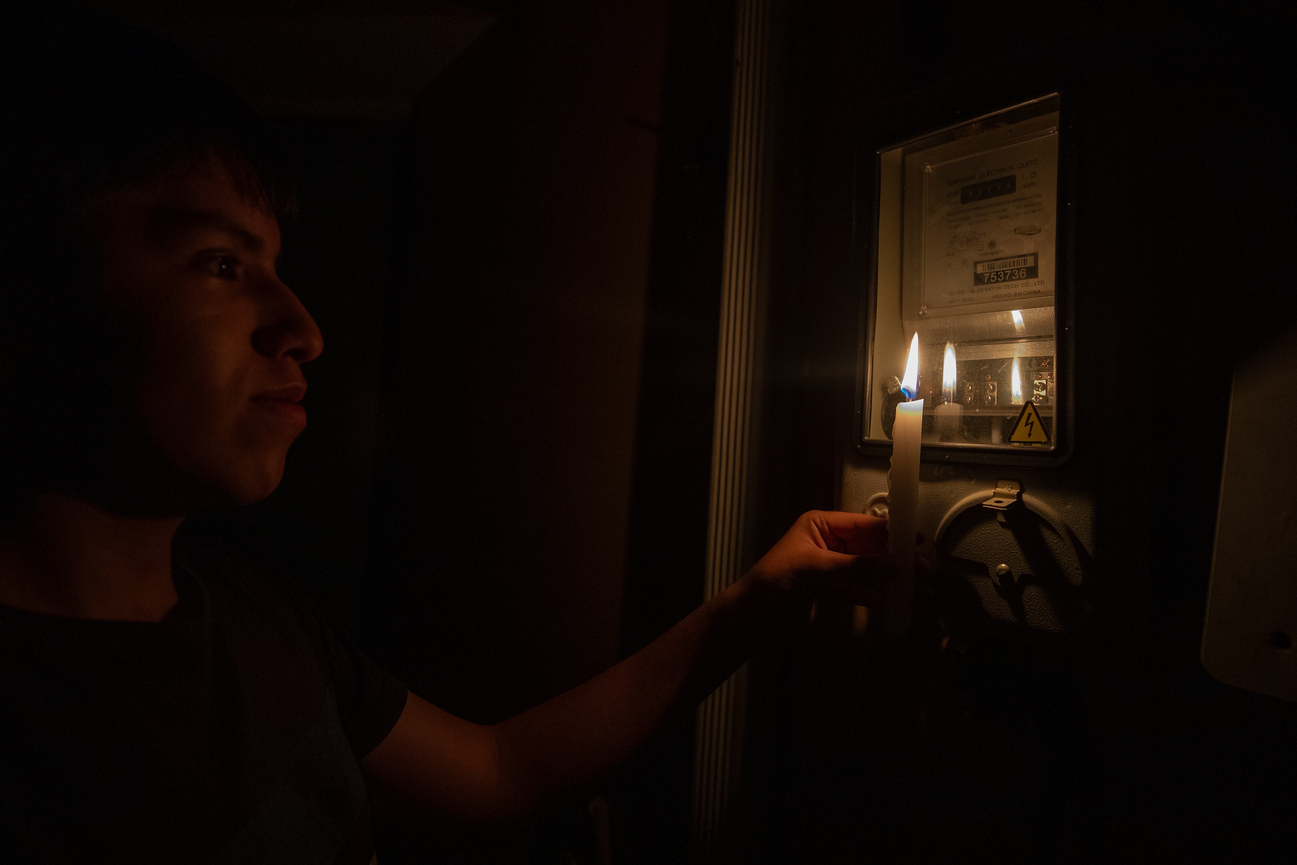 Un joven ecuatoriano revisa con una vela un medidor de luz este viernes en Quito (Ecuador). 
EFE/José Jácome