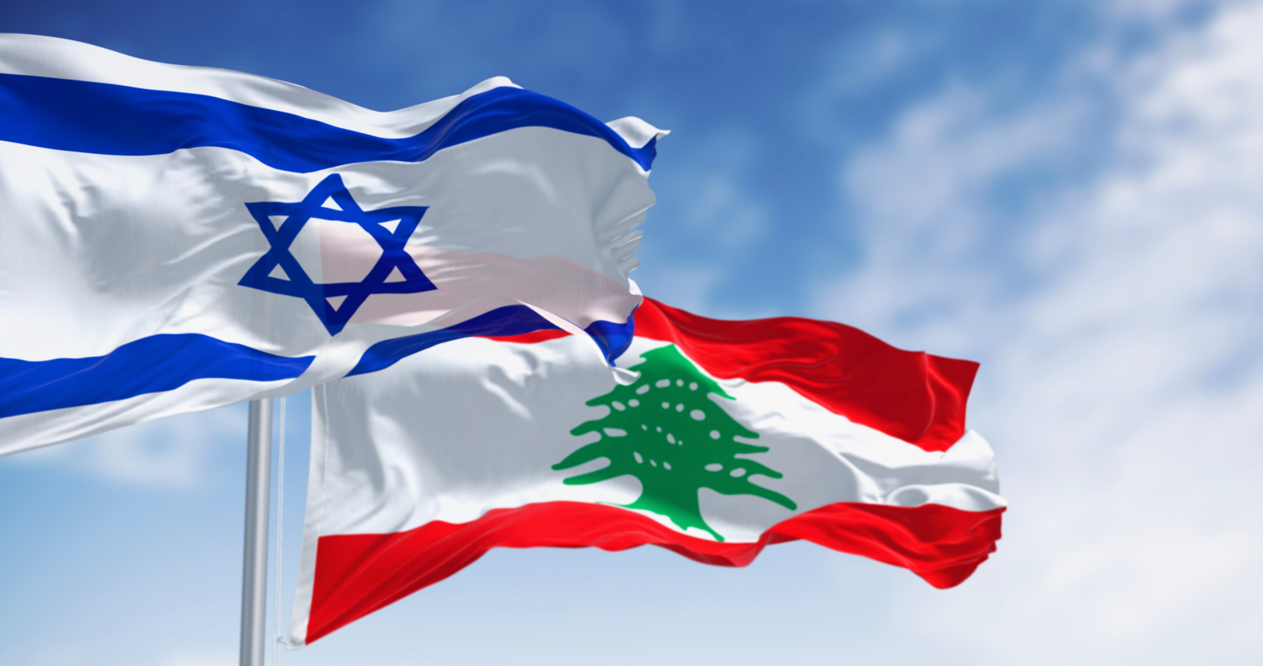 Flags of Israel and Lebanon waving in the wind on a clear day. Geopolitical instability and border security. 3d illustration render. Selective focus