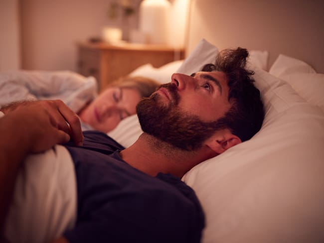 Hombre que sufre de insomnio, mientras su pareja duerme a su lado (Getty Images)