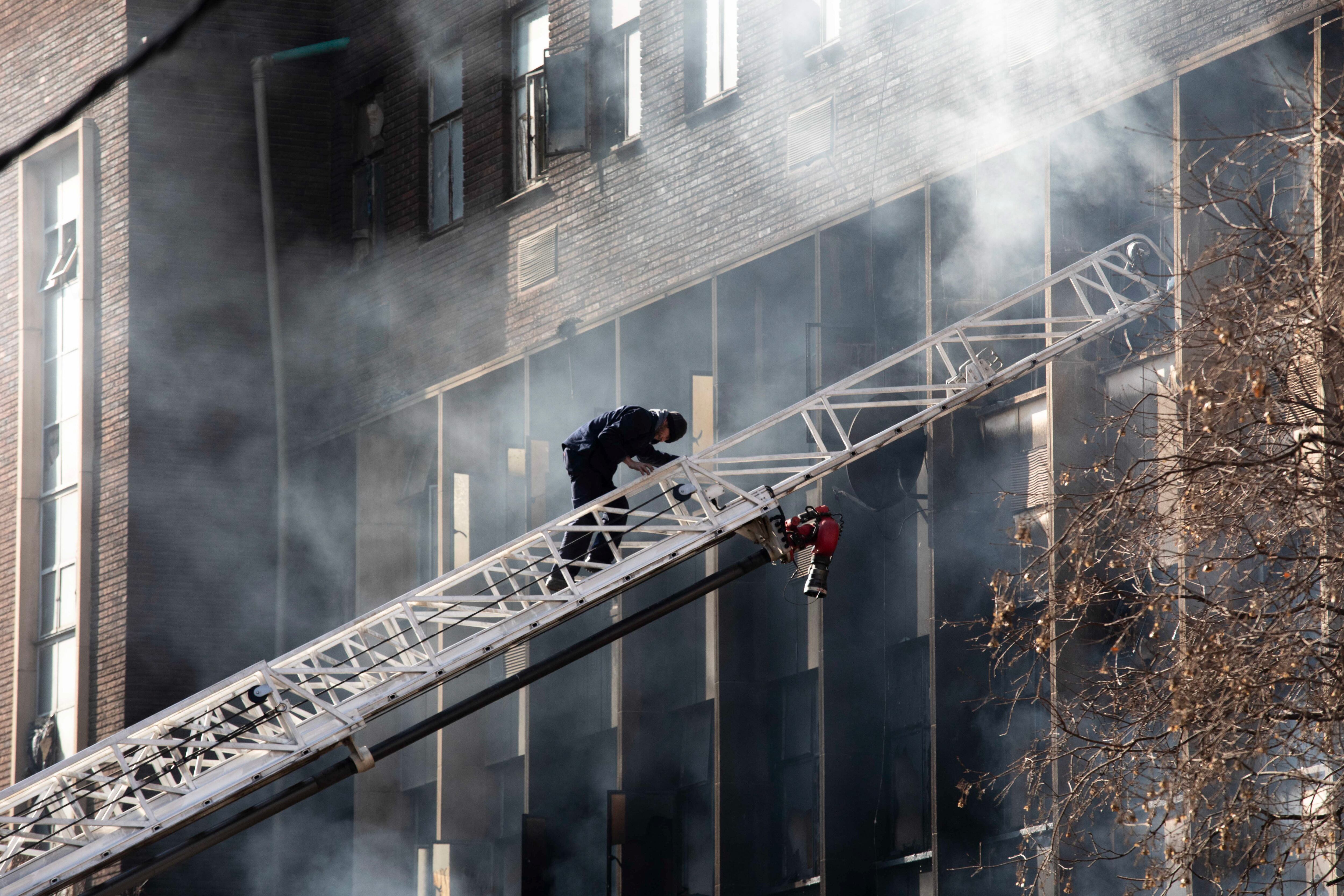 Johannesburg (South Africa), 31/08/2023.- An emergency services member climbs a ladder at the site of a fire that broke out at a five-storey building in the city centre, in Johannesburg, South Africa, 31 August 2023. More than 60 people have died following a fire that ravaged a building in central Johannesburg according to officials. (Sudáfrica, Johannesburgo) EFE/EPA/KIM LUDBROOK