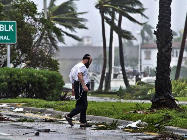 Un hombre camina junto a los escombros que han dejado los fuertes vientos durante el paso del huracán Irma por Miami Beach