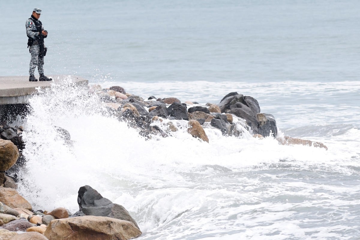 A member of Mexico's National Guard stands on the Puerto Vallarta boardwalk as waves crash against the shoreline ahead of the potential impact of Hurricane Simon in Puerto Vallarta, Jalisco state, Mexico, on October 11, 2026. Hurricane Simon strengthened into a powerful Category 4 storm and was expected to make landfall or skirt the coast of west-central Mexico on October 11, 2026, according to the US National Hurricane Center. (Photo by ULISES RUIZ / AFP)