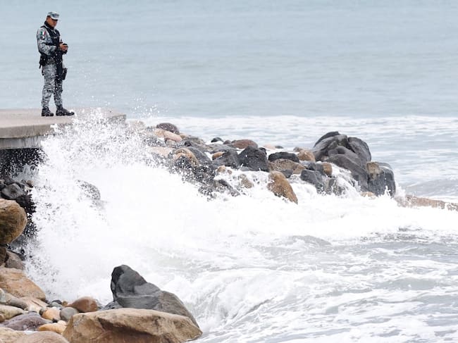 A member of Mexico's National Guard stands on the Puerto Vallarta boardwalk as waves crash against the shoreline ahead of the potential impact of Hurricane Simon in Puerto Vallarta, Jalisco state, Mexico, on October 11, 2026. Hurricane Simon strengthened into a powerful Category 4 storm and was expected to make landfall or skirt the coast of west-central Mexico on October 11, 2026, according to the US National Hurricane Center. (Photo by ULISES RUIZ / AFP)