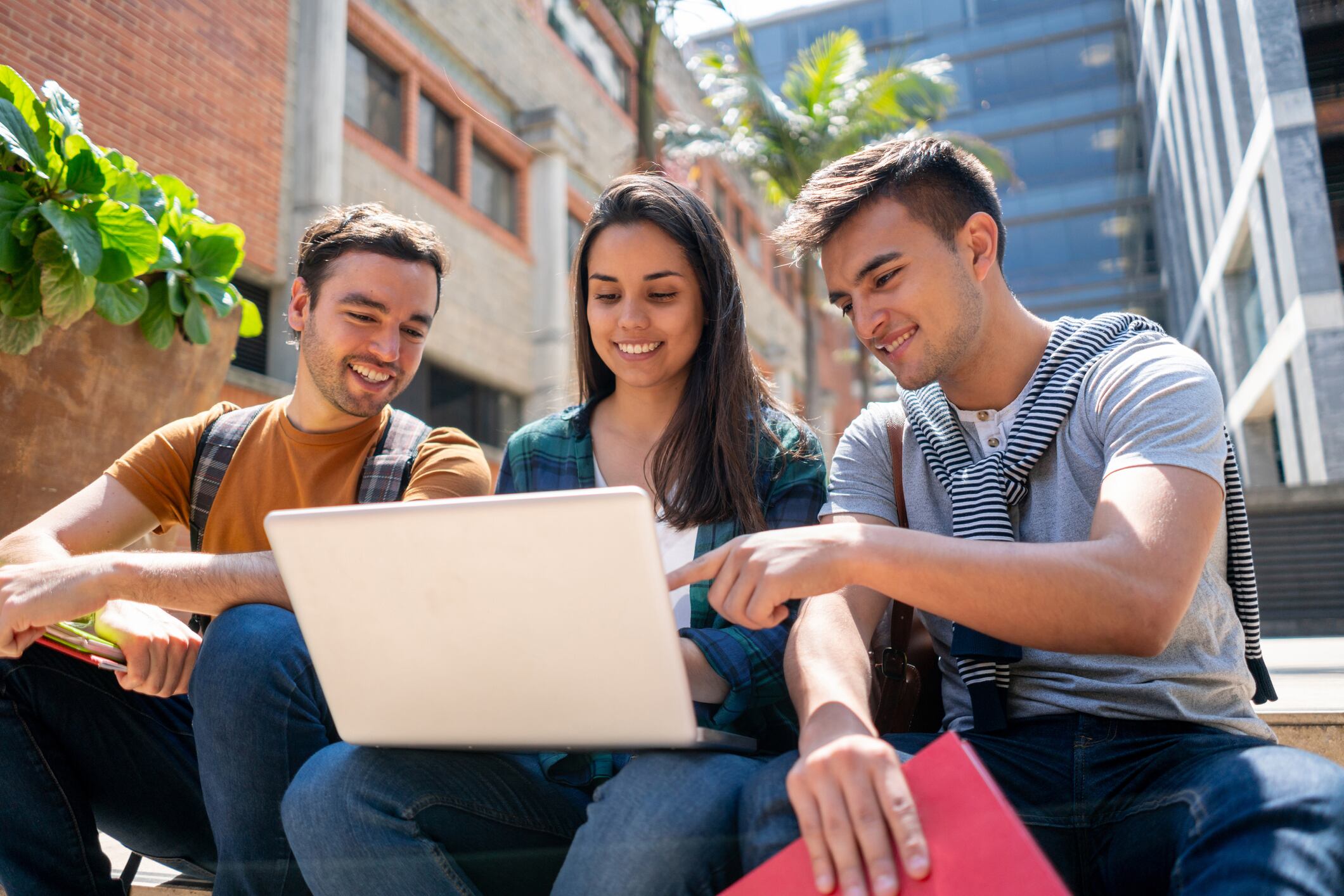 Jóvenes mirando el computador, sentados afuera de su universidad (Getty Images)