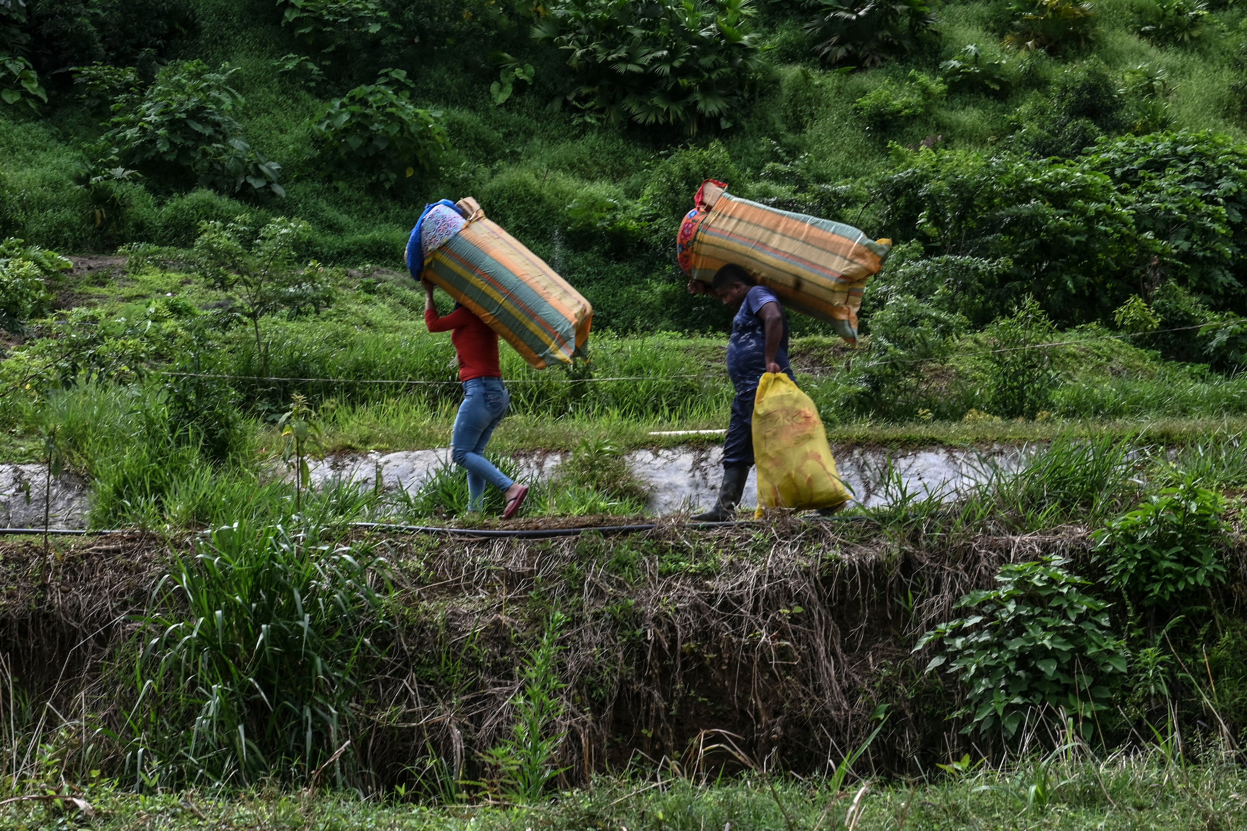 Former FARC guerillas carry their belongings as they arrive at a new reintegration zone in Mutata, Antioquia's Department, Colombia, on July 16, 2020 after being evacuated from the Territorial Area of Training and Reincorporation (ETCR) of Santa Lucia near Ituango. More than 90 ex-FARC (Revolutionary Armed Forces of Colombia) guerillas and their relatives were transferred from the Santa Lucia ETCR, after a series of deadly attacks that killed 11 demobilized FARC rebels there since the signing of the peace treaty between the FARC and the Colombian Government in 2016. (Photo by Joaquin SARMIENTO / AFP) (Photo by JOAQUIN SARMIENTO/AFP via Getty Images)
