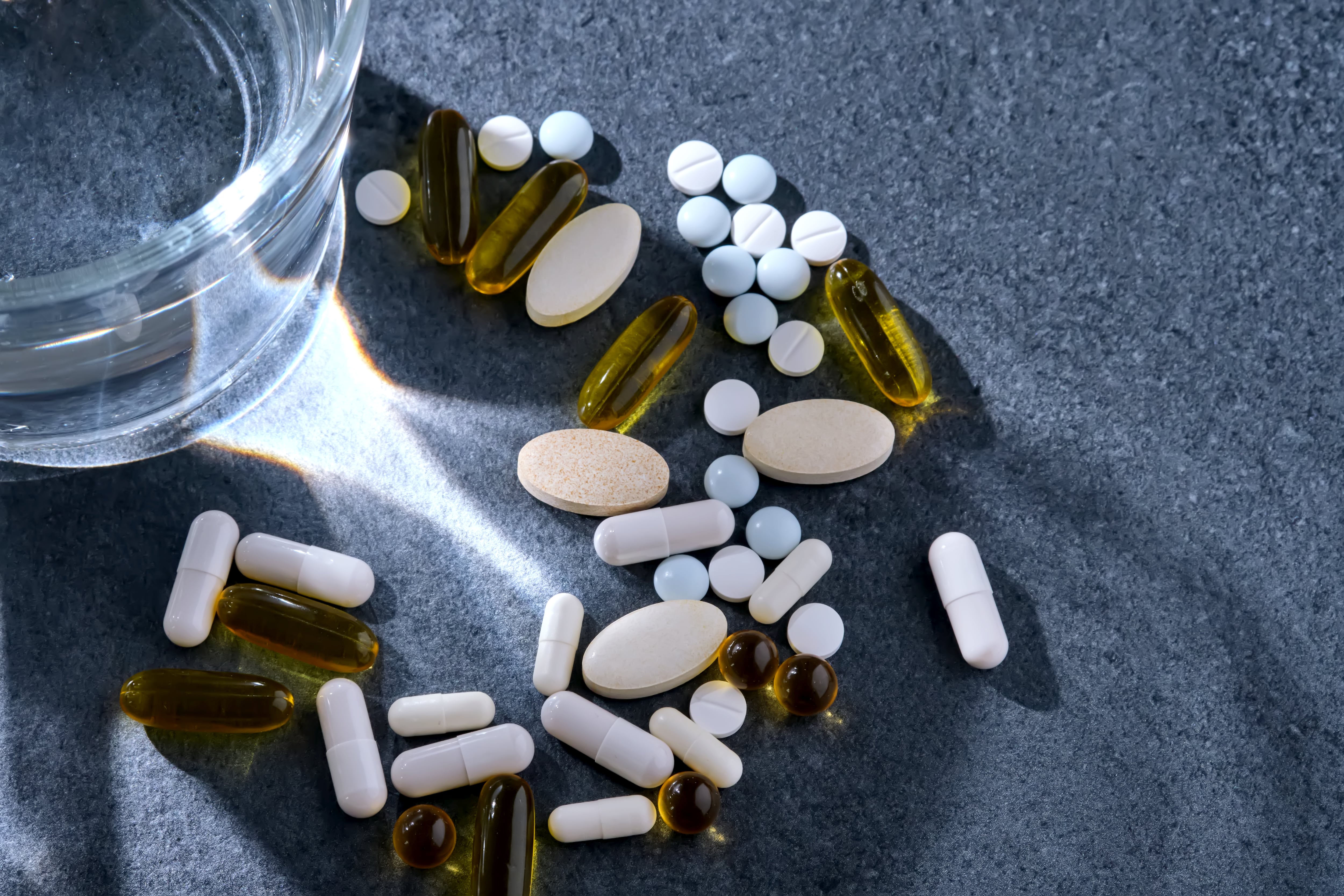 Variedad de pastillas junto a un vaso con agua. (Foto: Getty Images)