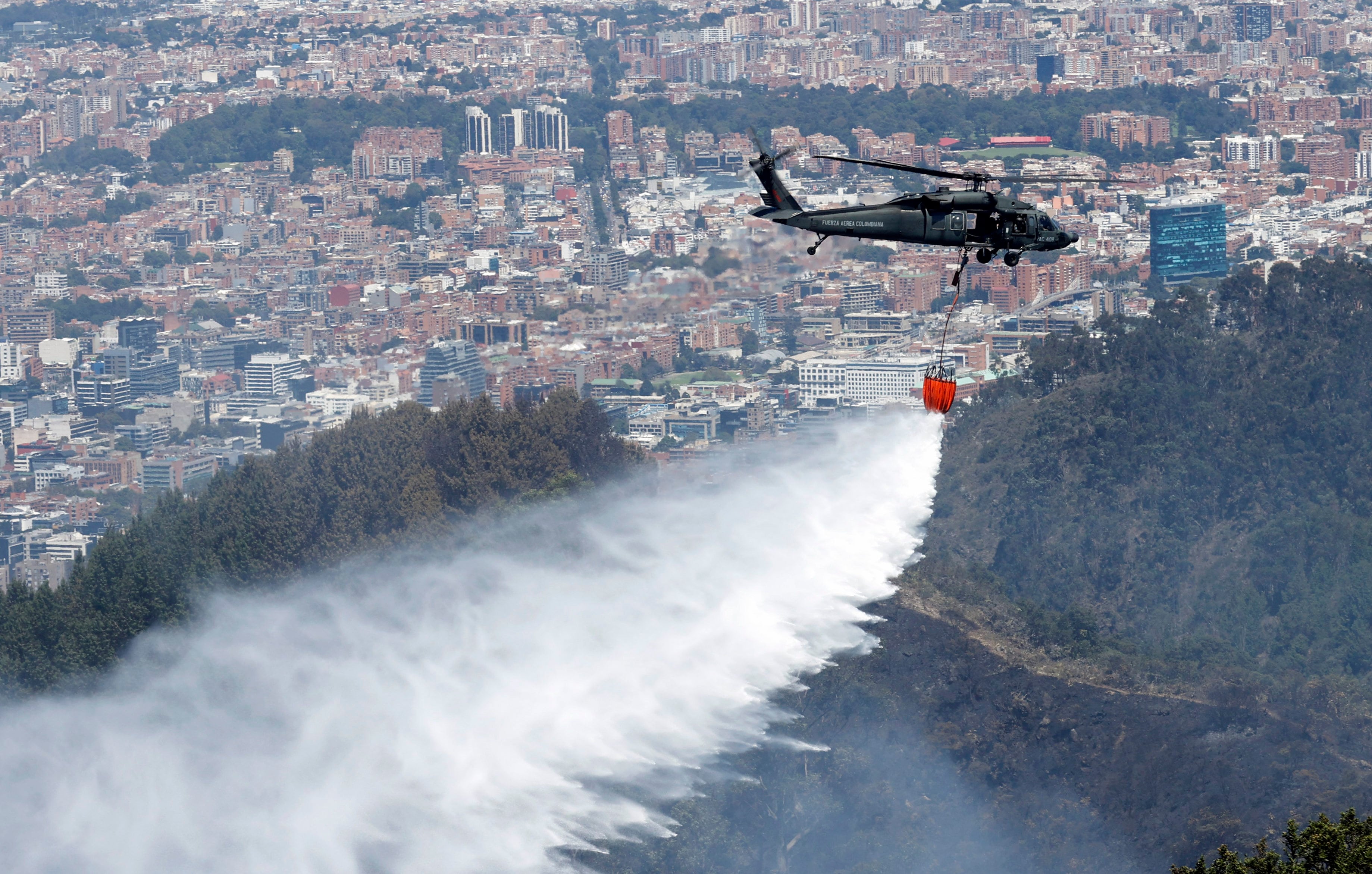 AME1624. BOGOTÁ (COLOMBIA), 23/01/2024.- Un helicóptero de la Fuerza Aérea Colombiana (FAC) participa hoy en labores de extinción de los incendios en los cerros orientales de Bogotá (Colombia). El incendio que comenzó ayer en los cerros orientales de Bogotá sigue activo y se ha extendido afectando a aproximadamente cuatro hectáreas de bosques en las últimas horas, aunque los bomberos aseguran que ya está "en control". EFE/ Mauricio Dueñas Castañeda