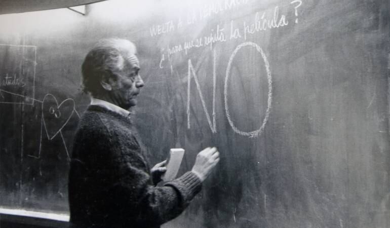 En el pizarrón dice “vuelta a la democracia para qué ¿para que se repita la película? No”. 