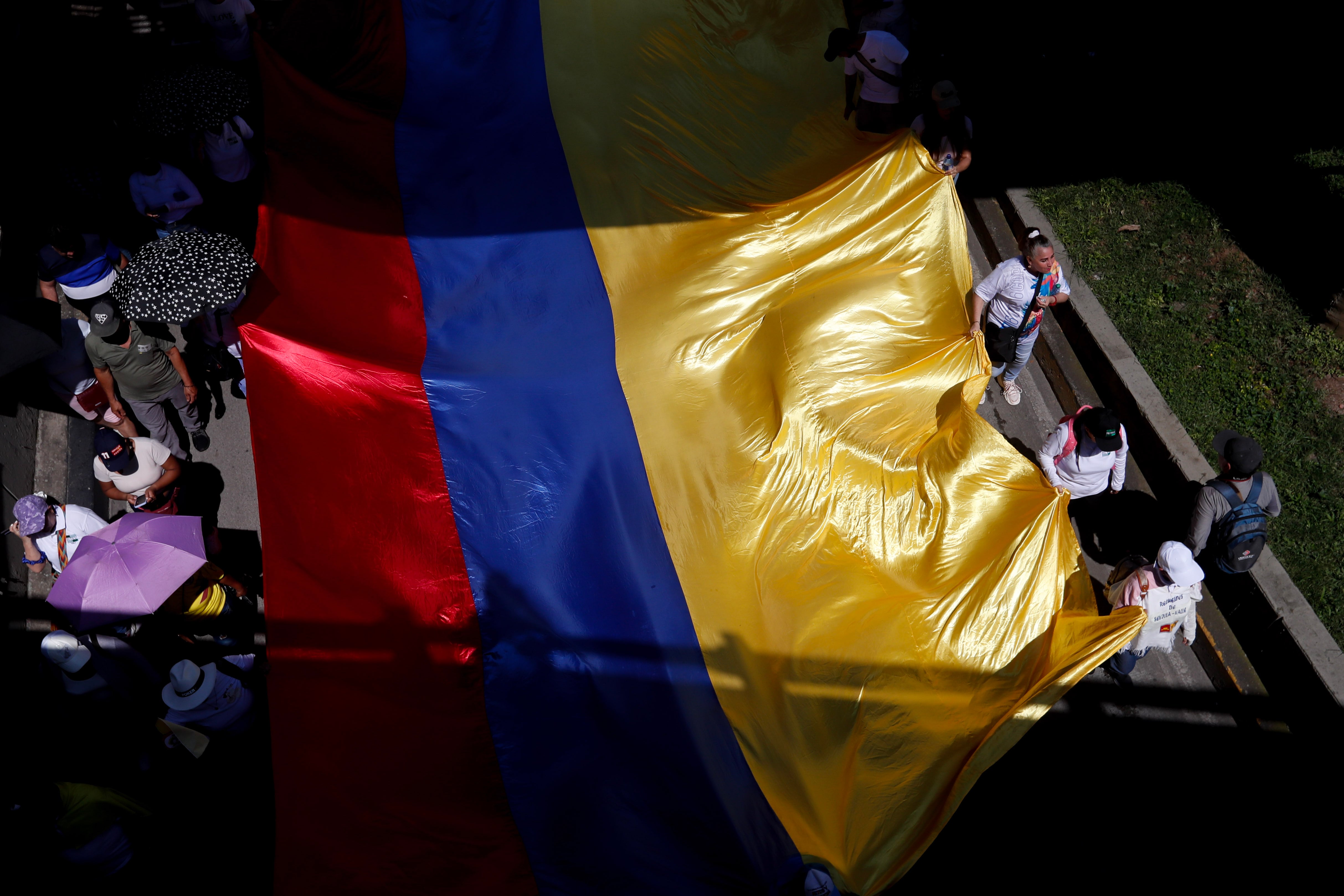 FOTODELDÍA AME1460. CALI (COLOMBIA), 28/05/2025.- Personas sostienen una bandera de Colombia durante el primer día de paro nacional este miércoles, en Cali (Colombia). El "gran paro nacional" de Colombia, convocado por centrales obreras para respaldar la consulta popular y las reformas sociales del Gobierno, comenzó con bloqueos de portales de transporte público en Bogotá y poca afluencia a las manifestaciones. EFE/ Ernesto Guzmán