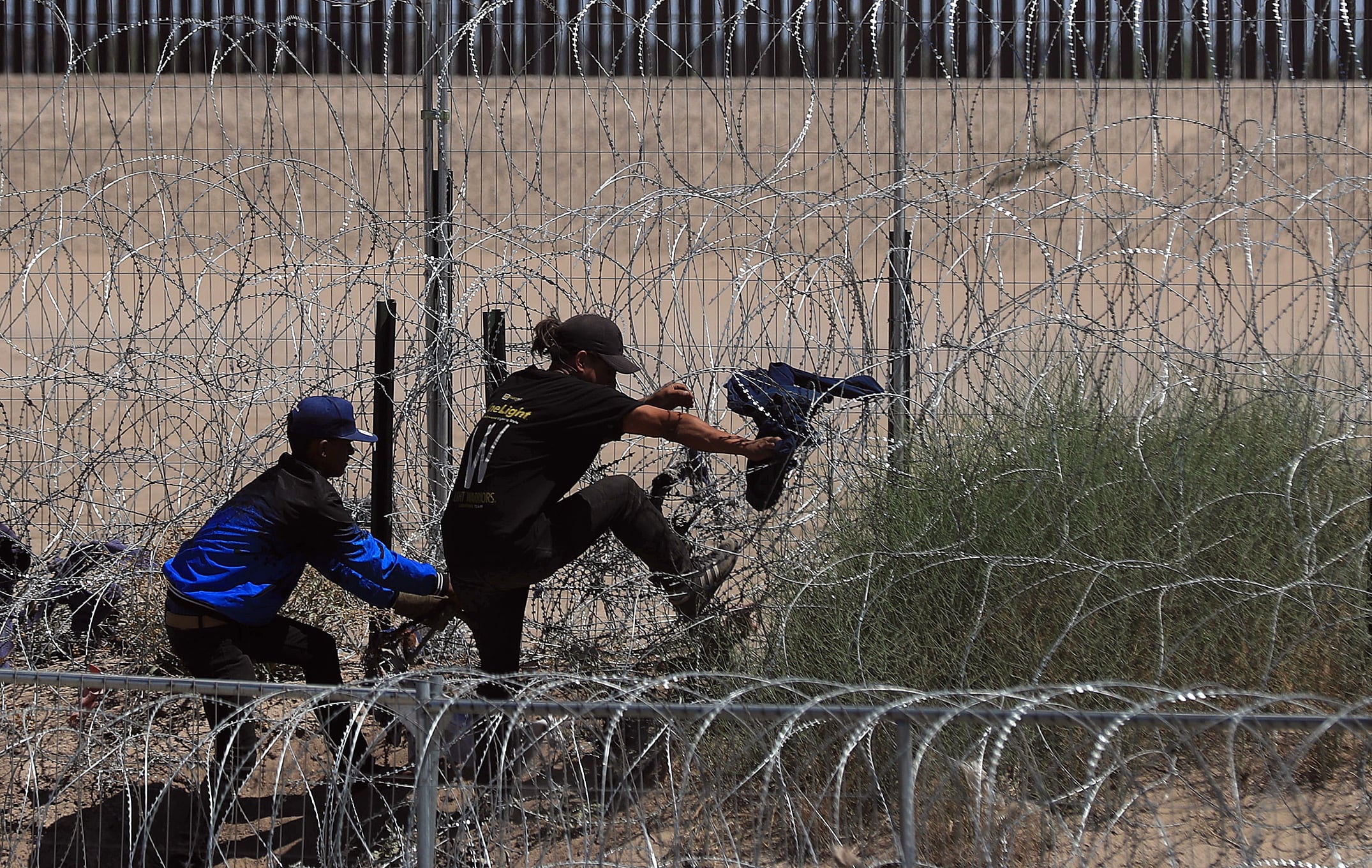 Migrantes intentan cruzar por una barricada de alambre con púas en las inmediaciones de la frontera con Estados Unidos.
 EFE/Luis Torres
