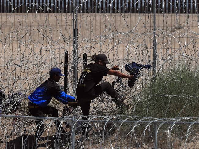 Migrantes intentan cruzar por una barricada de alambre con púas en las inmediaciones de la frontera con Estados Unidos.
EFE/Luis Torres