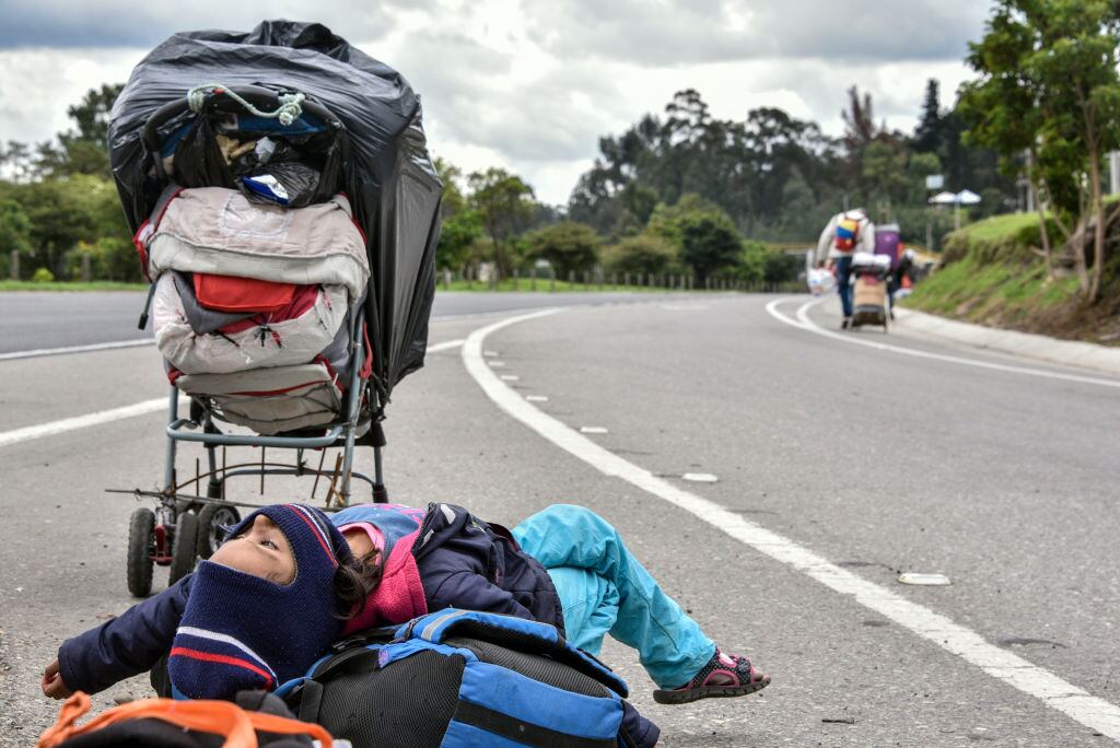 A Venezuelan migrant girl takes a break as others walk with their belongings on the highway on April 07, 2020 in Bogota, Colombia. Thousands of Venezuelan migrants living in Colombia have lost their jobs and in some cases been evicted from their homes due to the recession caused by the lock down to halt spread of COVID-19. Groups of Venezuelan gather in walking caravans and head the border crossing in Cúcuta, 550 km from Bogotá. According to UNHCR, Colombia hosts 1.3 million of Venezuelan migrants and refugees. (Photo by Guillermo Legaria/Getty Images)