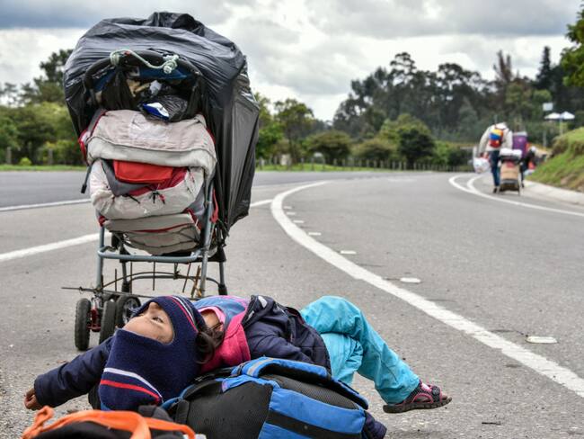 A Venezuelan migrant girl takes a break as others walk with their belongings on the highway on April 07, 2020 in Bogota, Colombia. Thousands of Venezuelan migrants living in Colombia have lost their jobs and in some cases been evicted from their homes due to the recession caused by the lock down to halt spread of COVID-19. Groups of Venezuelan gather in walking caravans and head the border crossing in Cúcuta, 550 km from Bogotá. According to UNHCR, Colombia hosts 1.3 million of Venezuelan migrants and refugees. (Photo by Guillermo Legaria/Getty Images)