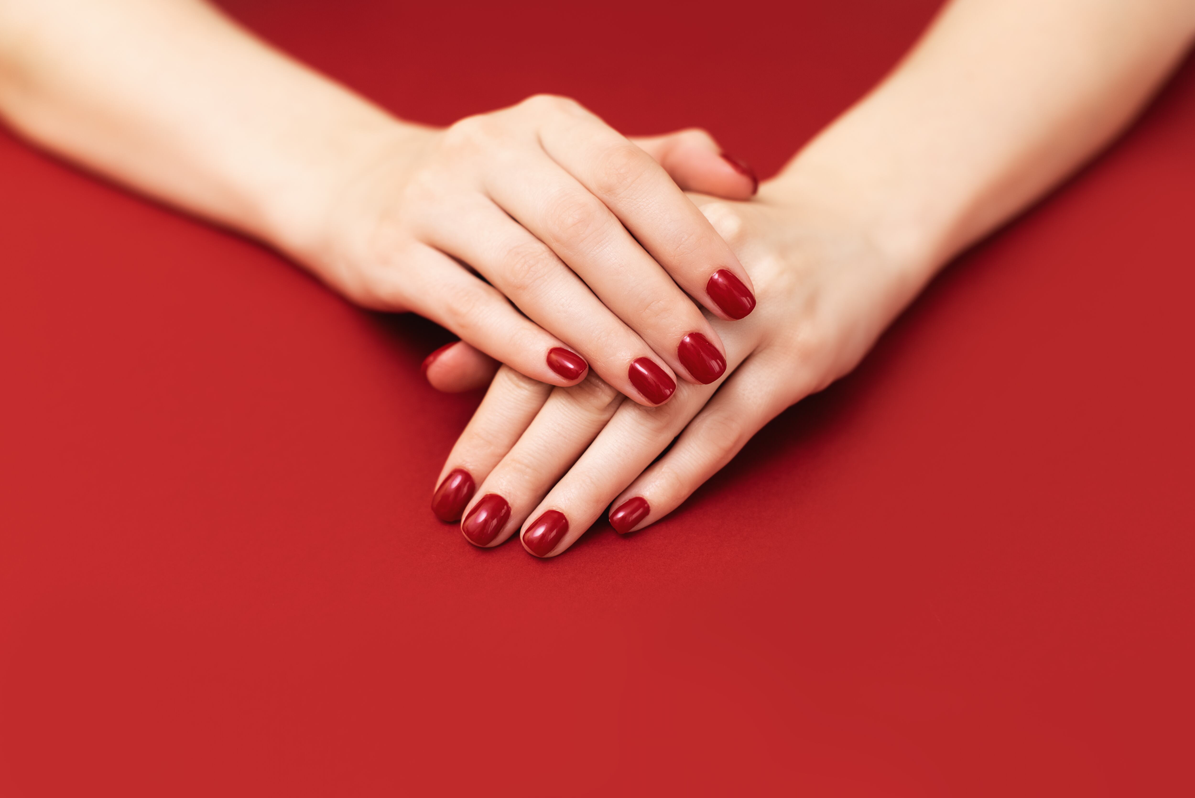 Manos de mujer con las uñas pintadas de rojo, sobre un fondo del mismo color. (Foto: Getty Images)