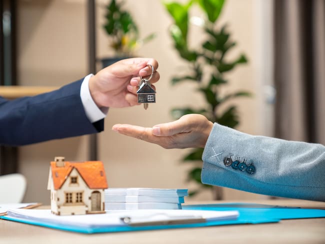Estate agent giving house keys to woman and sign agreement in office
