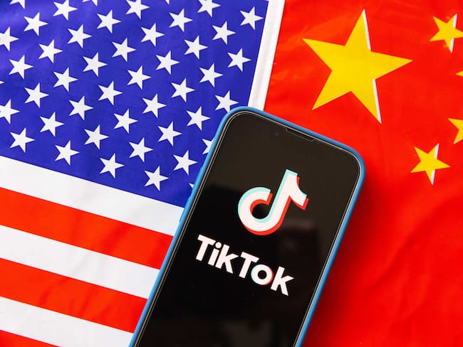Ilustración: un teléfono móvil muestra el logotipo de TikTok con las banderas de Estados Unidos y la República Popular China al fondo. (Ilustración fotográfica de Stanislav Kogiku/SOPA Images/LightRocket vía Getty Images)