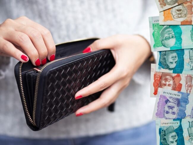 Imagen de referencia // mujer con una billetera y billetes colombianos