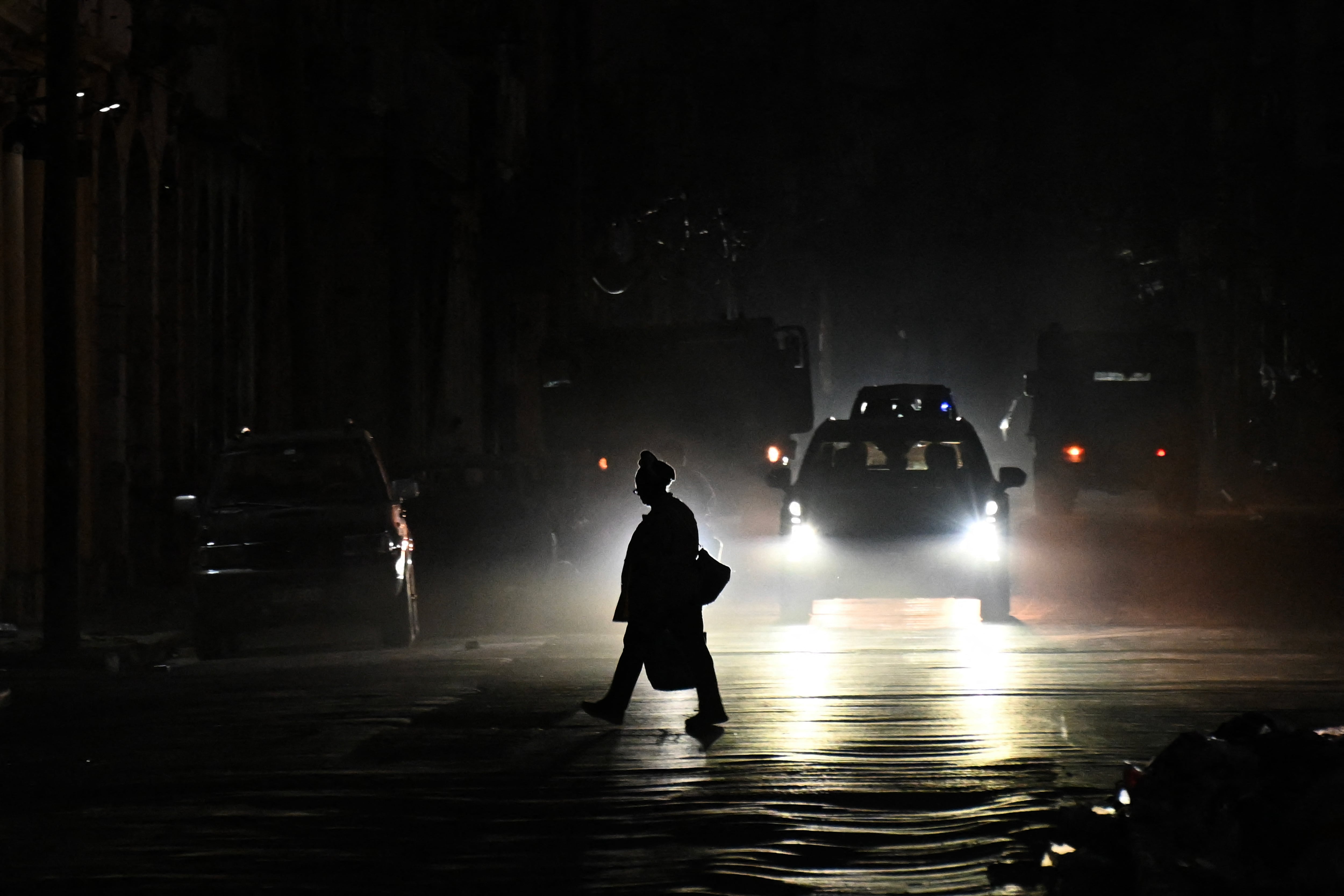 A person crosses a street during a nationwide blackout in Havana on July 10, 2026. Cuba suffered its second nationwide blackout in five days on July 10 as twin energy and economic crises, compounded by a six-month US fuel blockade, caused the electricity grid to collapse. (Photo by YAMIL LAGE / AFP)