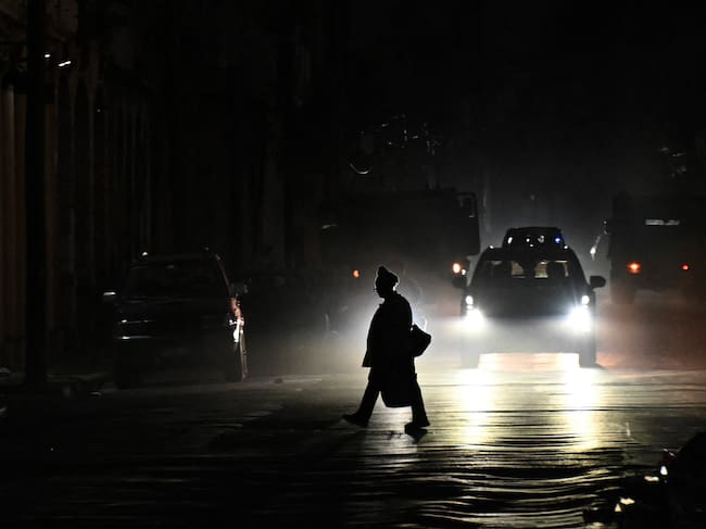 A person crosses a street during a nationwide blackout in Havana on July 10, 2026. Cuba suffered its second nationwide blackout in five days on July 10 as twin energy and economic crises, compounded by a six-month US fuel blockade, caused the electricity grid to collapse. (Photo by YAMIL LAGE / AFP)