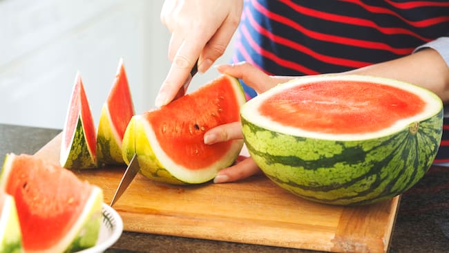 Persona cortando una sandía (Foto vía Getty Images)