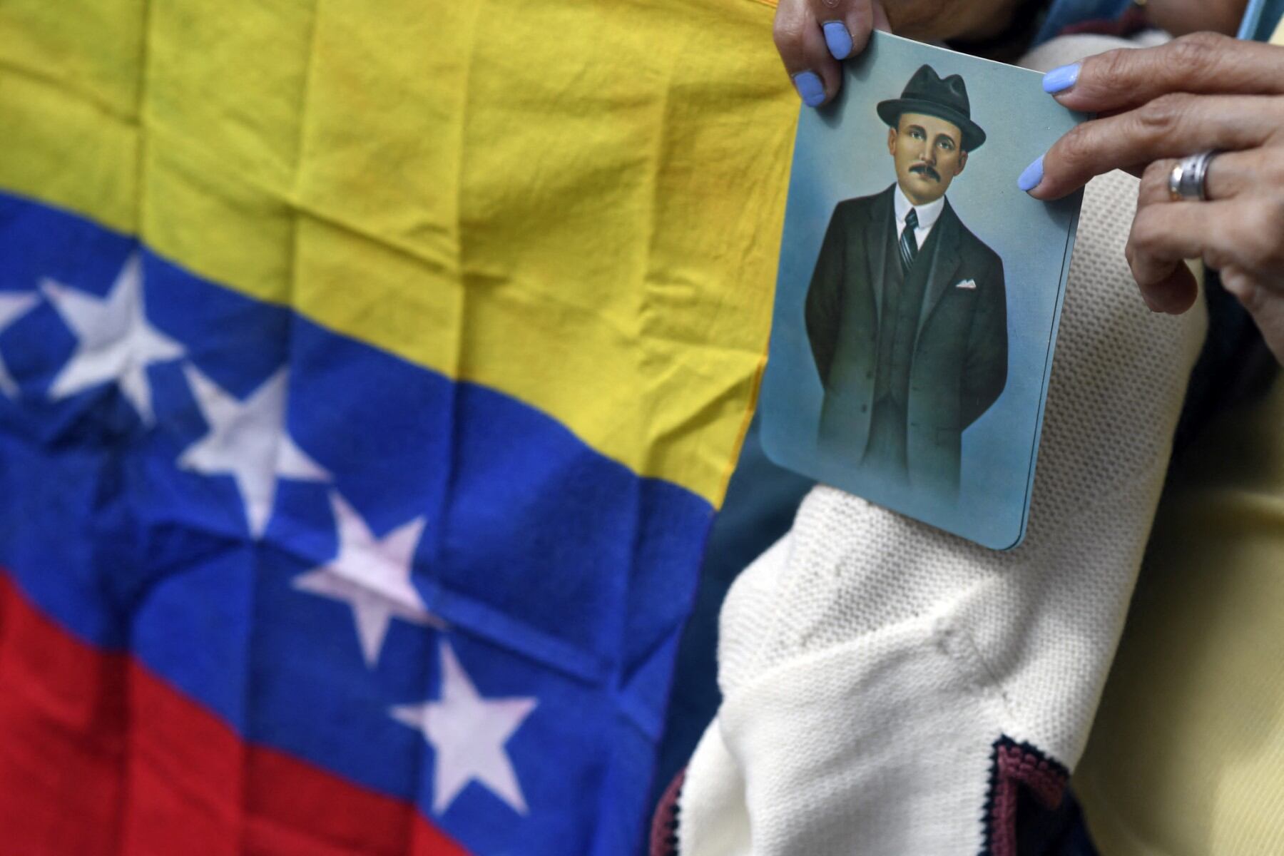 A woman holds an image of Venezuelan doctor Jose Gregorio Hernandez, also called "the doctor of the poor", during his beatification ceremony outside La Candelaria church  in Caracas on April 30, 2021. A Venezuelan physician who died more than 100 years ago and is revered as a "doctor of the poor" for his selfless service during a previous pandemic, was beatified by the Catholic Church Friday, a step towards sainthood. (Photo by Federico Parra / AFP)