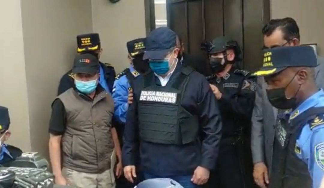 El expresidente hondureño, Juan Orlando Hernández, recibe un chaleco antibalas antes de ser esposado por la Policía.        Foto: @PolicíaHonduras  Policía de Honduras 