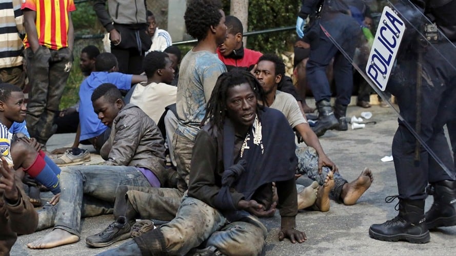 Migrantes sentados en el suelo junto a policías españoles tras cruzar una cerca para entrar en el enclave español de Ceuta, en España, el viernes 17 de febrero de 2017. Foto: Associated Press - AP