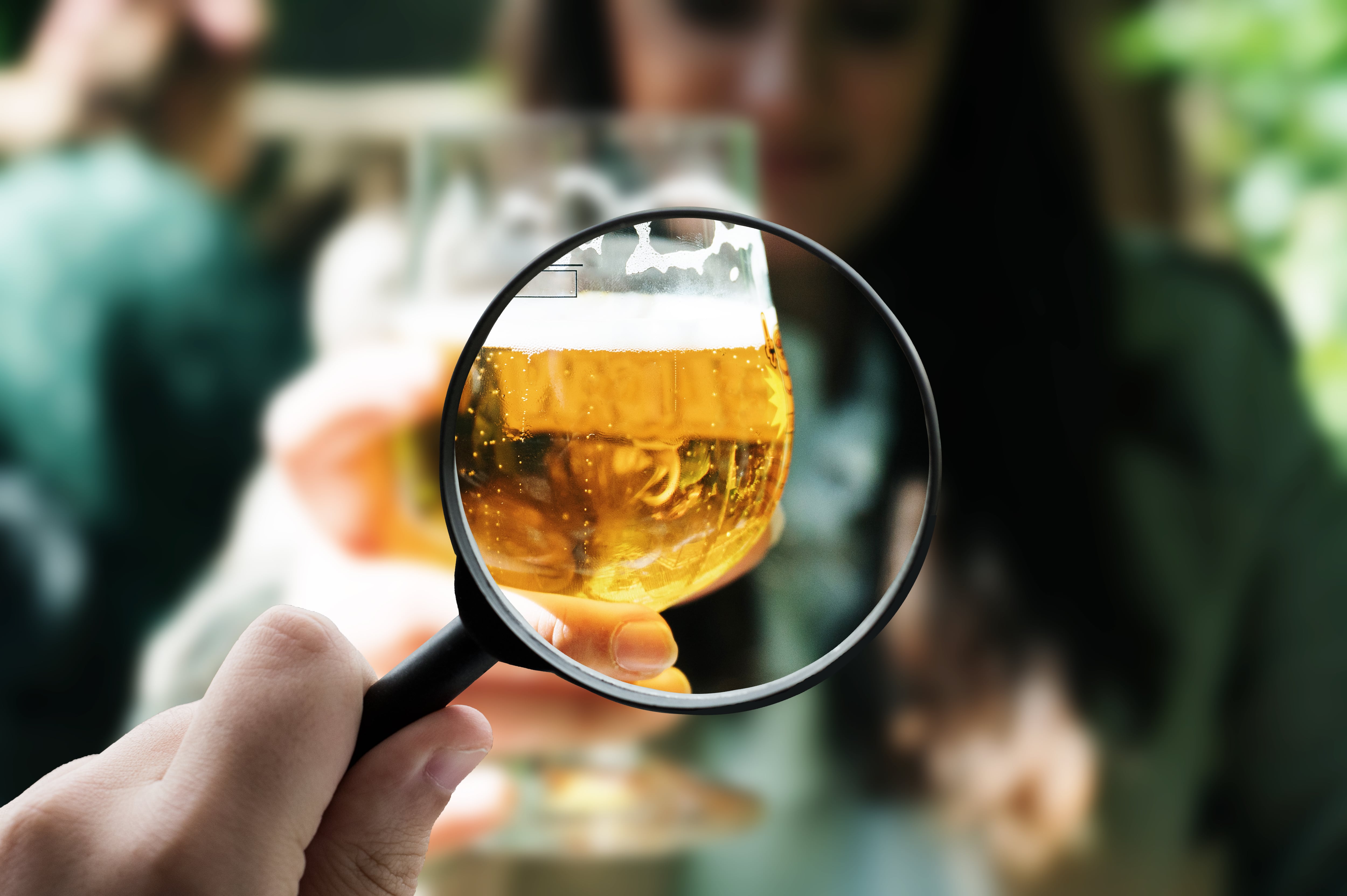 Persona mirando cuidadosamente una cerveza, a través de una lupa (Getty Images)