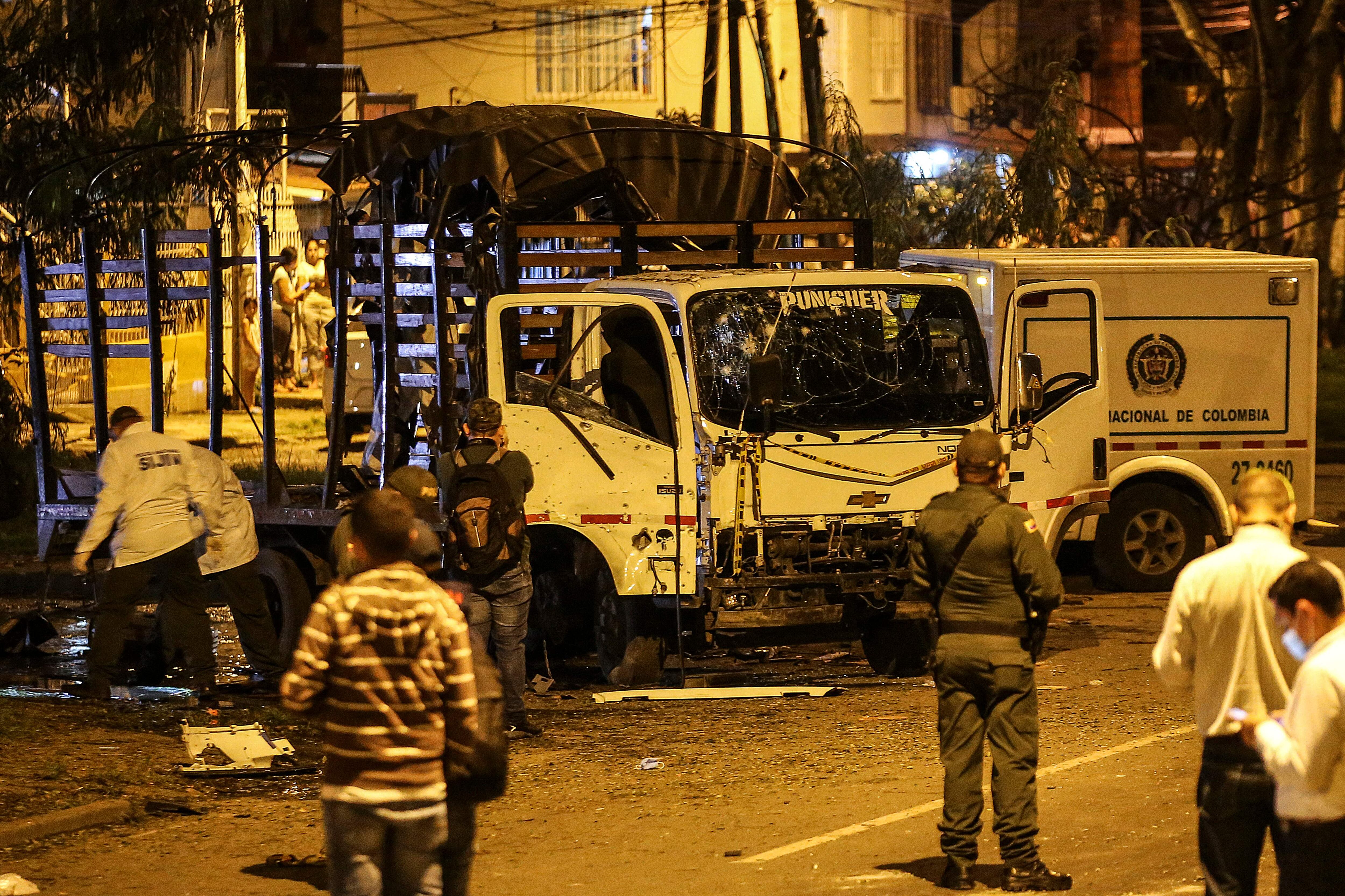 Security personnel inspect a national police truck destroyed by an explosive device in Cali, Colombia on January 8, 2022. - The explosion injured ten police officers and no deaths have been reported yet. (Photo by Paola MAFLA / AFP) (Photo by PAOLA MAFLA/AFP via Getty Images)