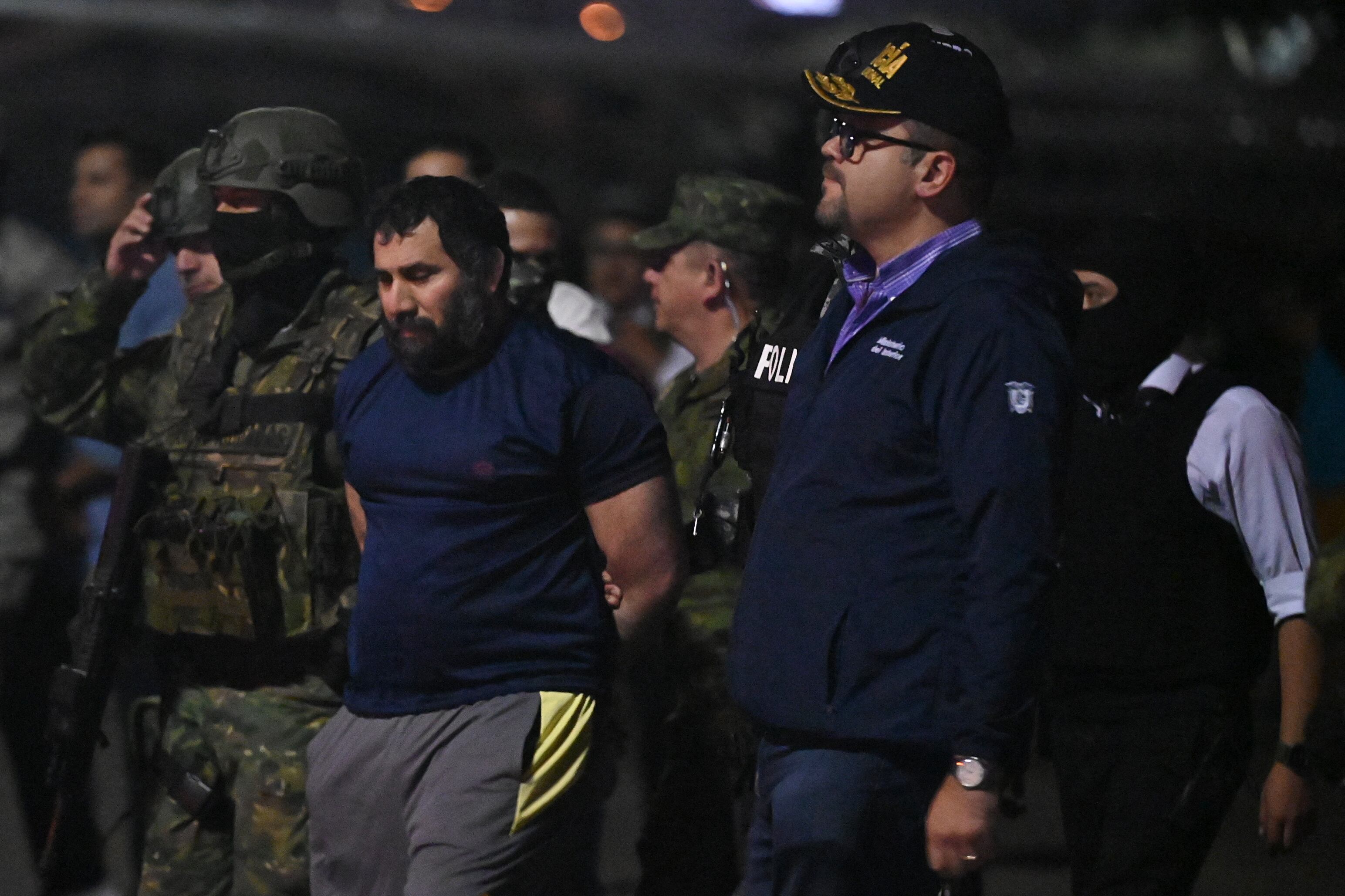 Drug trafficker Adolfo Macias (C), alias Fito, is guarded by Ecuador's Interior Minister John Reimberg (2nd R) and military personnel upon arrival at the air base in Guayaquil, Ecuador, on June 25, 2025, after his recapture in Manta, Manabi Province. Ecuadorian security forces recaptured fugitive "Fito," the country's most wanted drug trafficker, whose escape in January 2024 sparked an unprecedented wave of violence, President Daniel Noboa reported on June 25. (Photo by MARCOS PIN / AFP) (Photo by MARCOS PIN/AFP via Getty Images)          