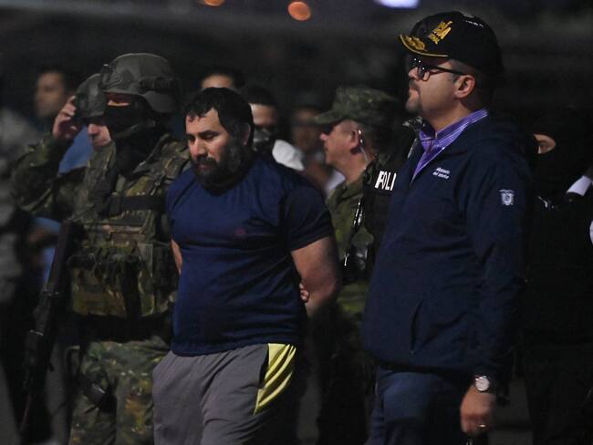 Drug trafficker Adolfo Macias (C), alias Fito, is guarded by Ecuador's Interior Minister John Reimberg (2nd R) and military personnel upon arrival at the air base in Guayaquil, Ecuador, on June 25, 2025, after his recapture in Manta, Manabi Province. Ecuadorian security forces recaptured fugitive "Fito," the country's most wanted drug trafficker, whose escape in January 2024 sparked an unprecedented wave of violence, President Daniel Noboa reported on June 25. (Photo by MARCOS PIN / AFP) (Photo by MARCOS PIN/AFP via Getty Images)