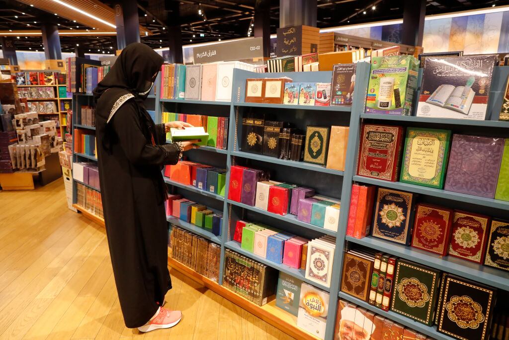 Muslim woman wearing Abaya choosing  Quran in a bookshop.  Dubai. United Arab Emirates. (Photo by: Philippe Lissac/Godong/Universal Images Group via Getty Images)