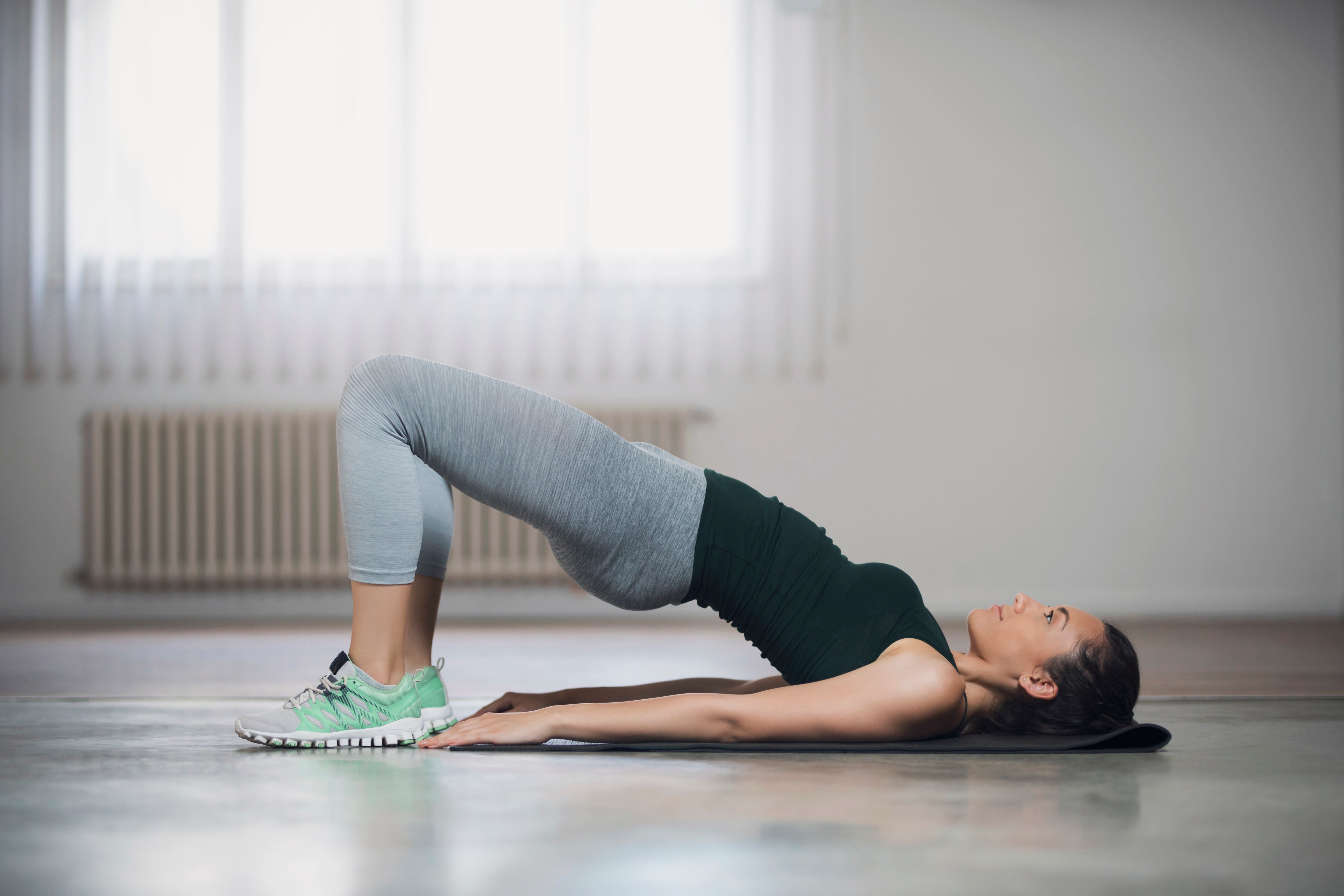 Mujer realizando ejercicio para glúteos en el suelo (Getty Images)