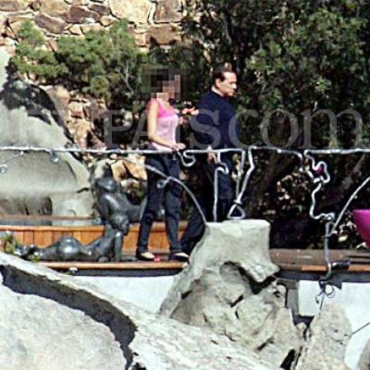 Una invitada pasea por la mansión de Berlusconi vigilada por un escolta
